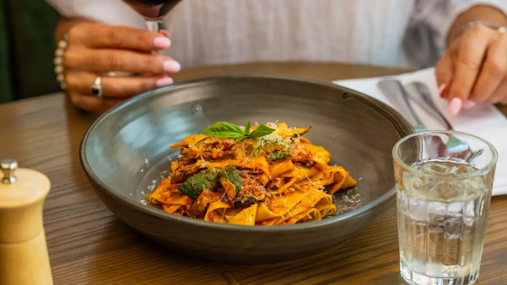 Pappardelle pasta with a rich tomato-based sauce, grilled vegetables, and fresh basil,