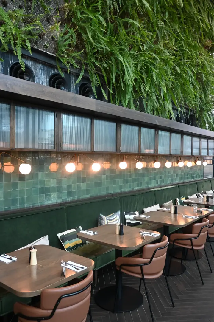 Dining area at THIRTEEN50 Kitchen & Bar Auckland Airport with booth seating and greenery