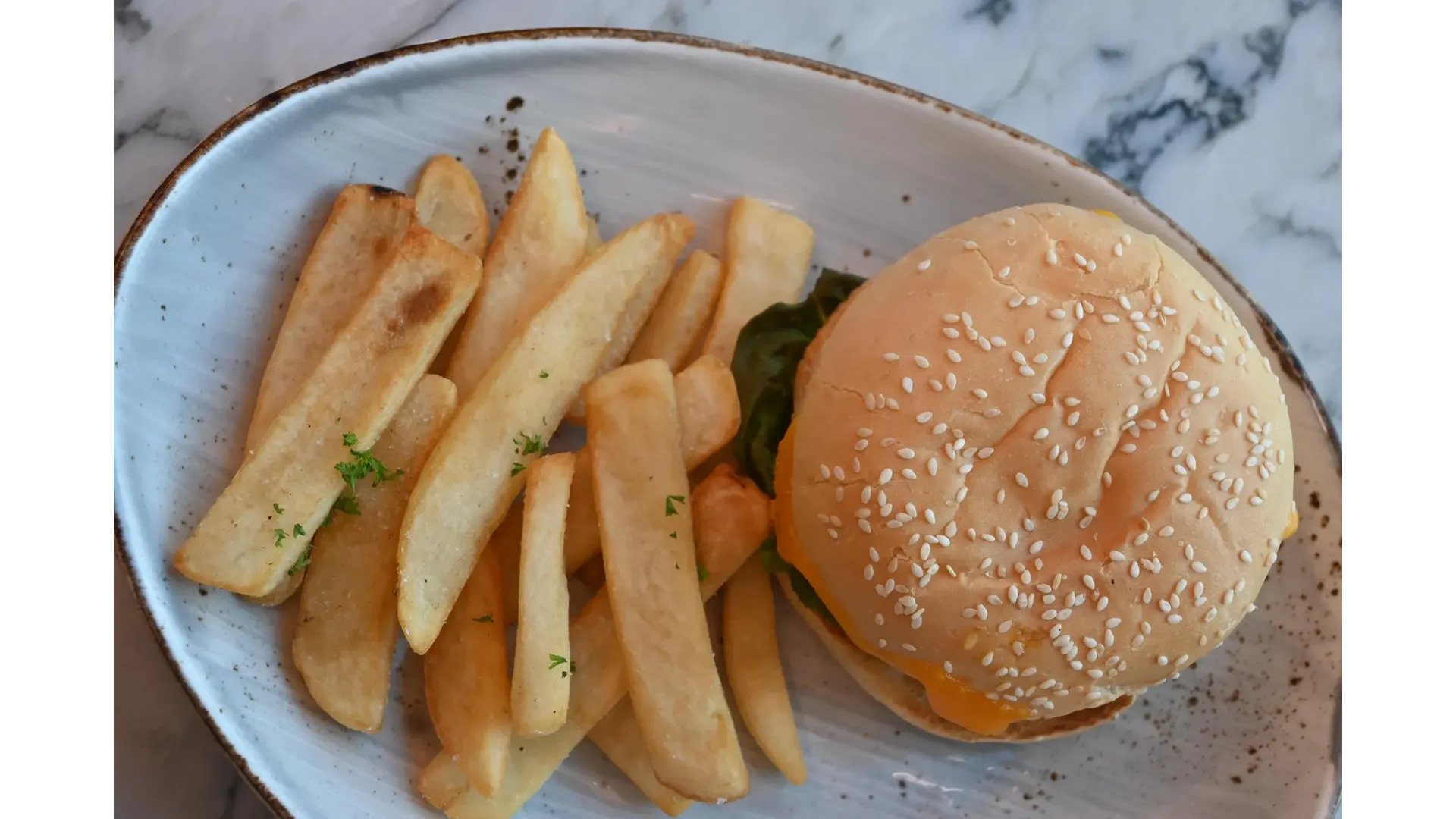 A classic comfort combo at Thirteen 50 Kitchen & Bar Auckland — a juicy cheeseburger on a sesame bun paired with golden, thick-cut fries.